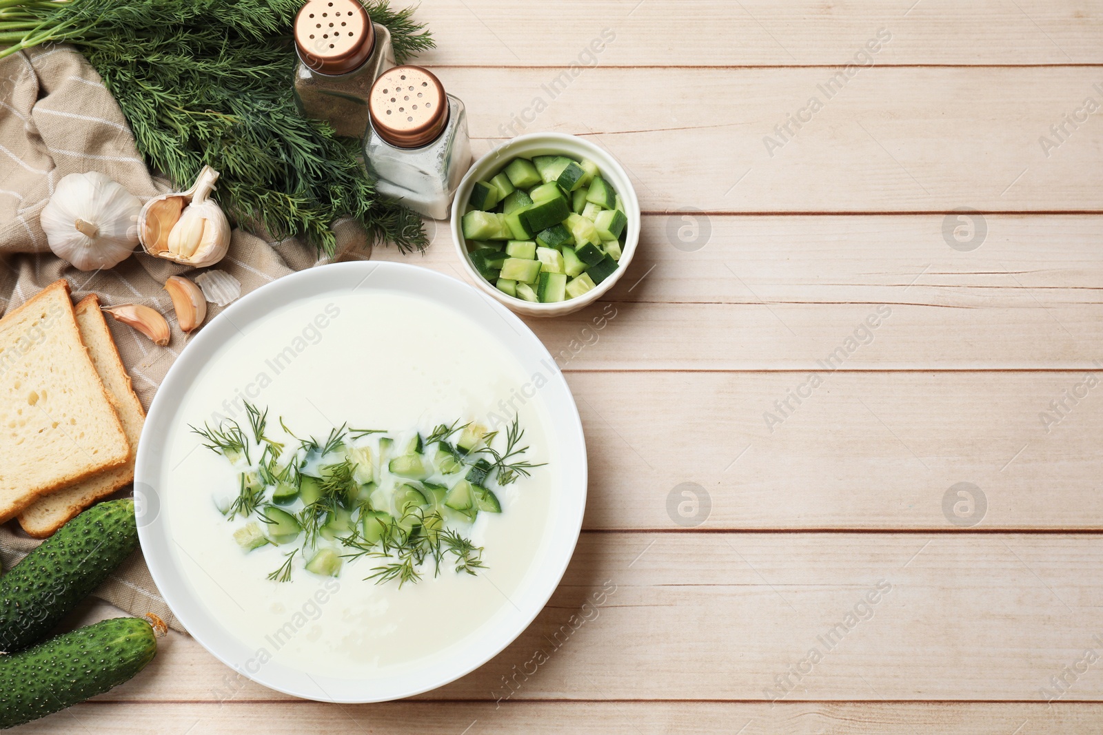 Tasty cucumber soup in bowl and ingredients on light wooden table, flat lay. Space for text Photo of Tasty cucumber soup in bowl and ingredients on light wooden table, flat lay. Space for text