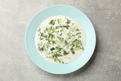 Photo of Tasty cucumber soup with dill on grey textured table, top view