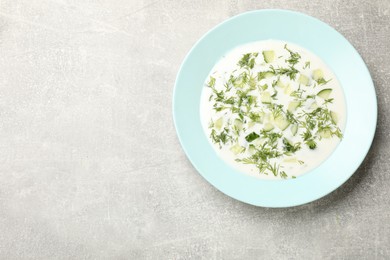 Photo of Tasty cucumber soup with dill on grey textured table, top view. Space for text