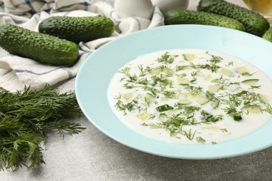 Photo of Tasty cucumber soup with dill on grey textured table, closeup