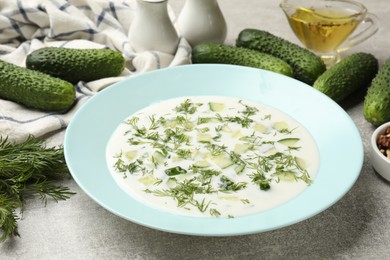 Photo of Tasty cucumber soup with dill on grey textured table, closeup