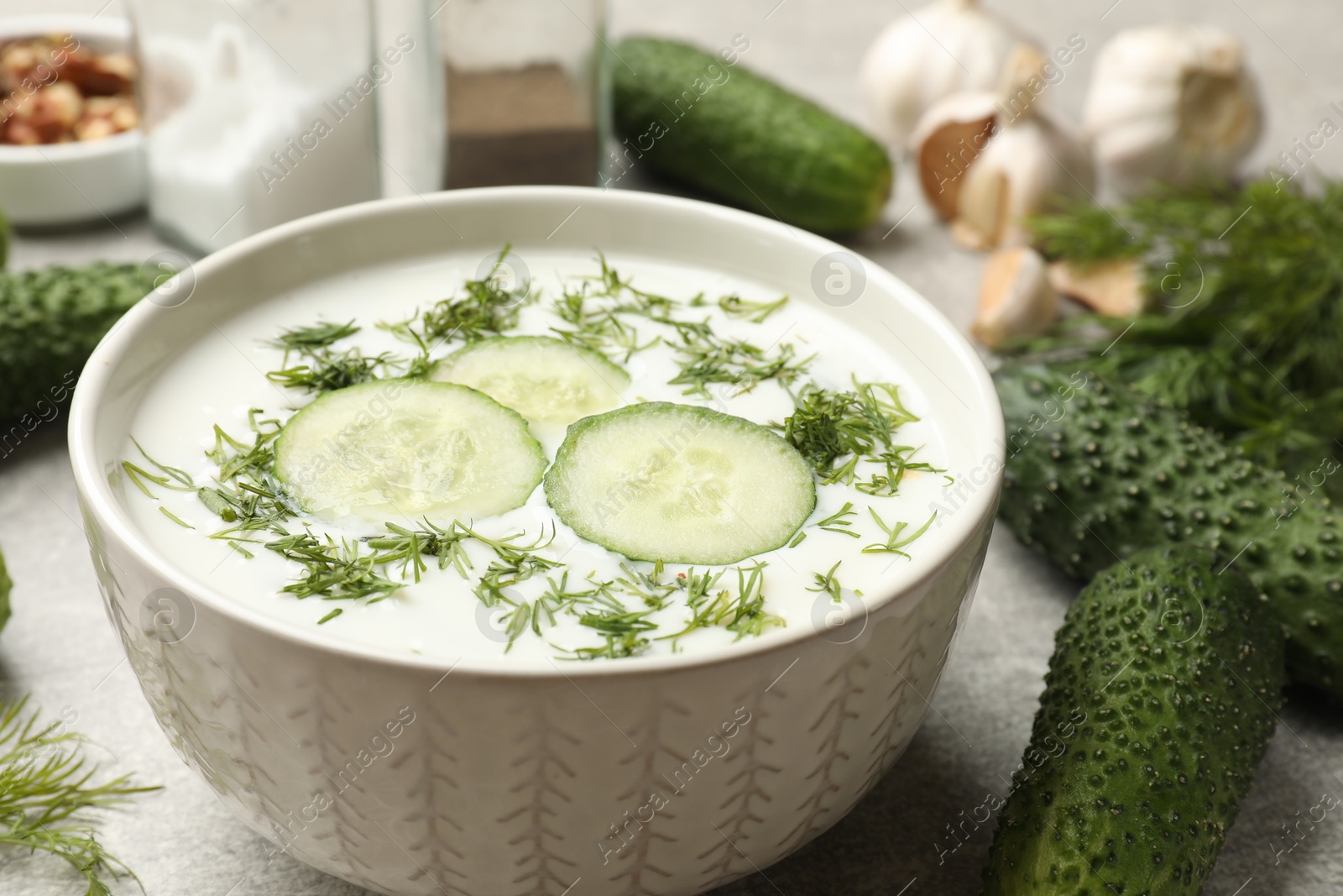 Tasty cucumber soup with dill in bowl on grey textured table, closeup Photo of Tasty cucumber soup with dill in bowl on grey textured table, closeup