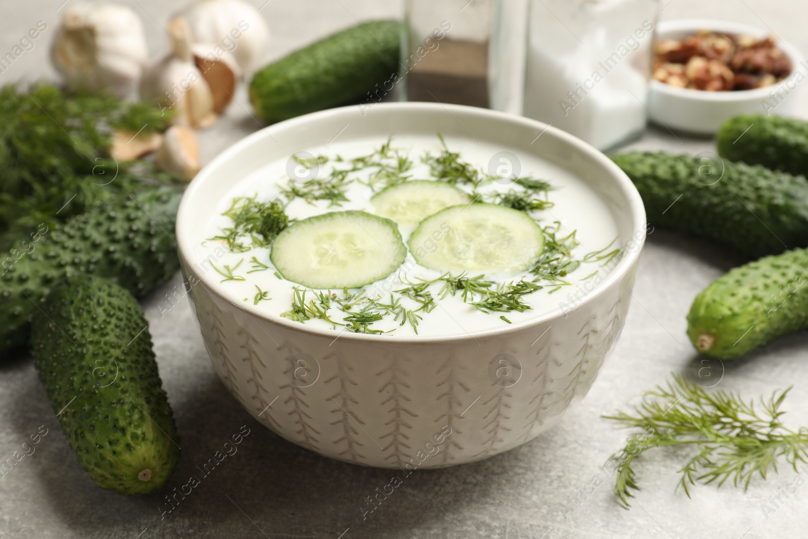 Tasty cucumber soup with dill in bowl on grey textured table, closeup Photo of Tasty cucumber soup with dill in bowl on grey textured table, closeup