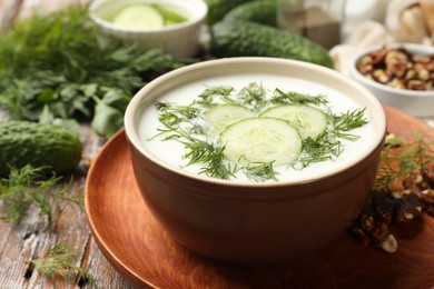 Photo of Tasty cucumber soup with dill and nuts on wooden table, closeup