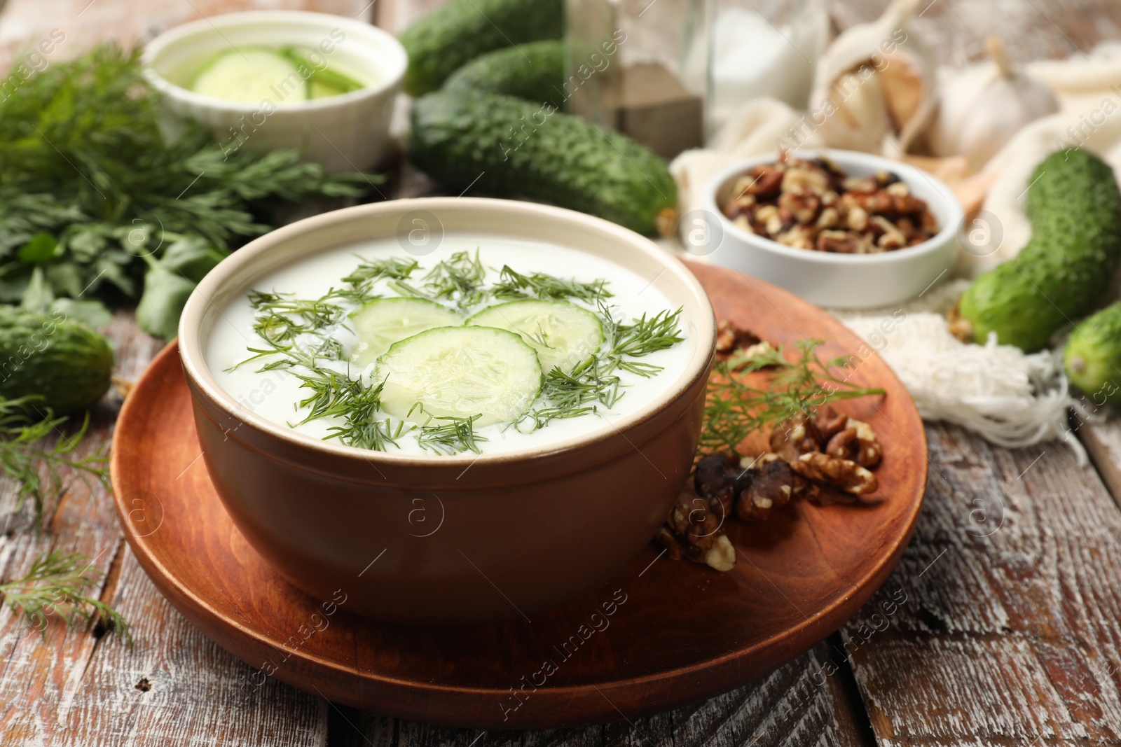 Tasty cucumber soup with dill and nuts on wooden table, closeup Photo of Tasty cucumber soup with dill and nuts on wooden table, closeup