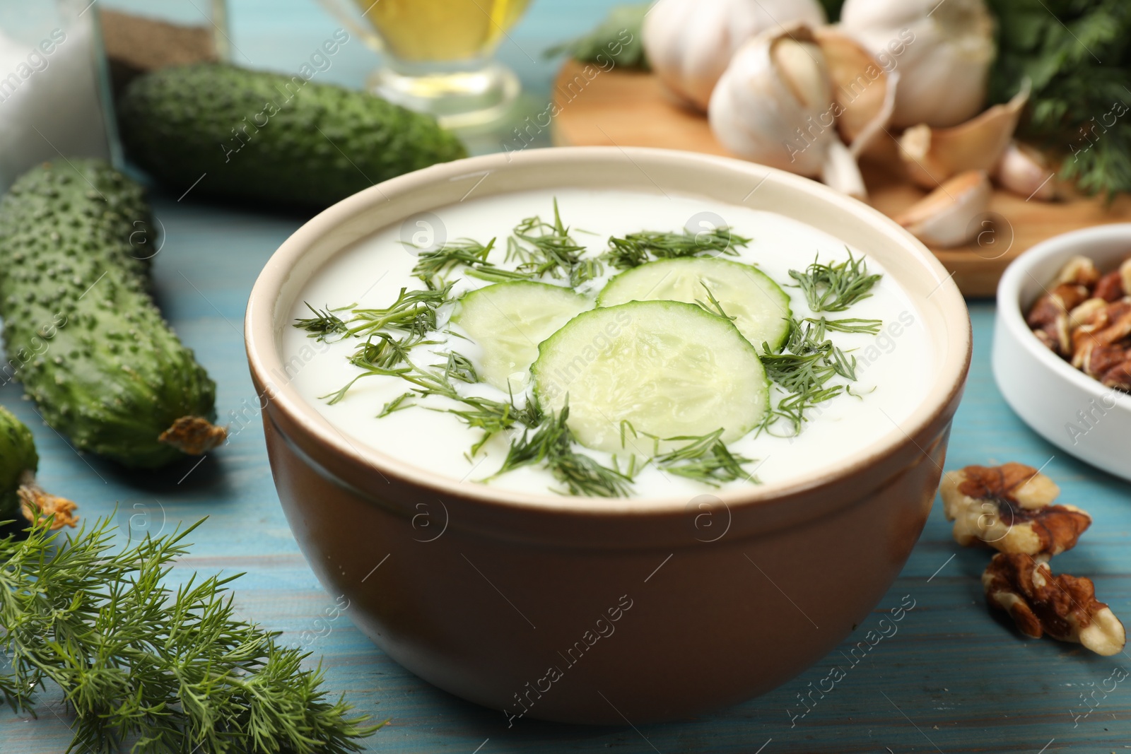 Tasty cucumber soup with dill among products on light blue wooden table, closeup Photo of Tasty cucumber soup with dill among products on light blue wooden table, closeup