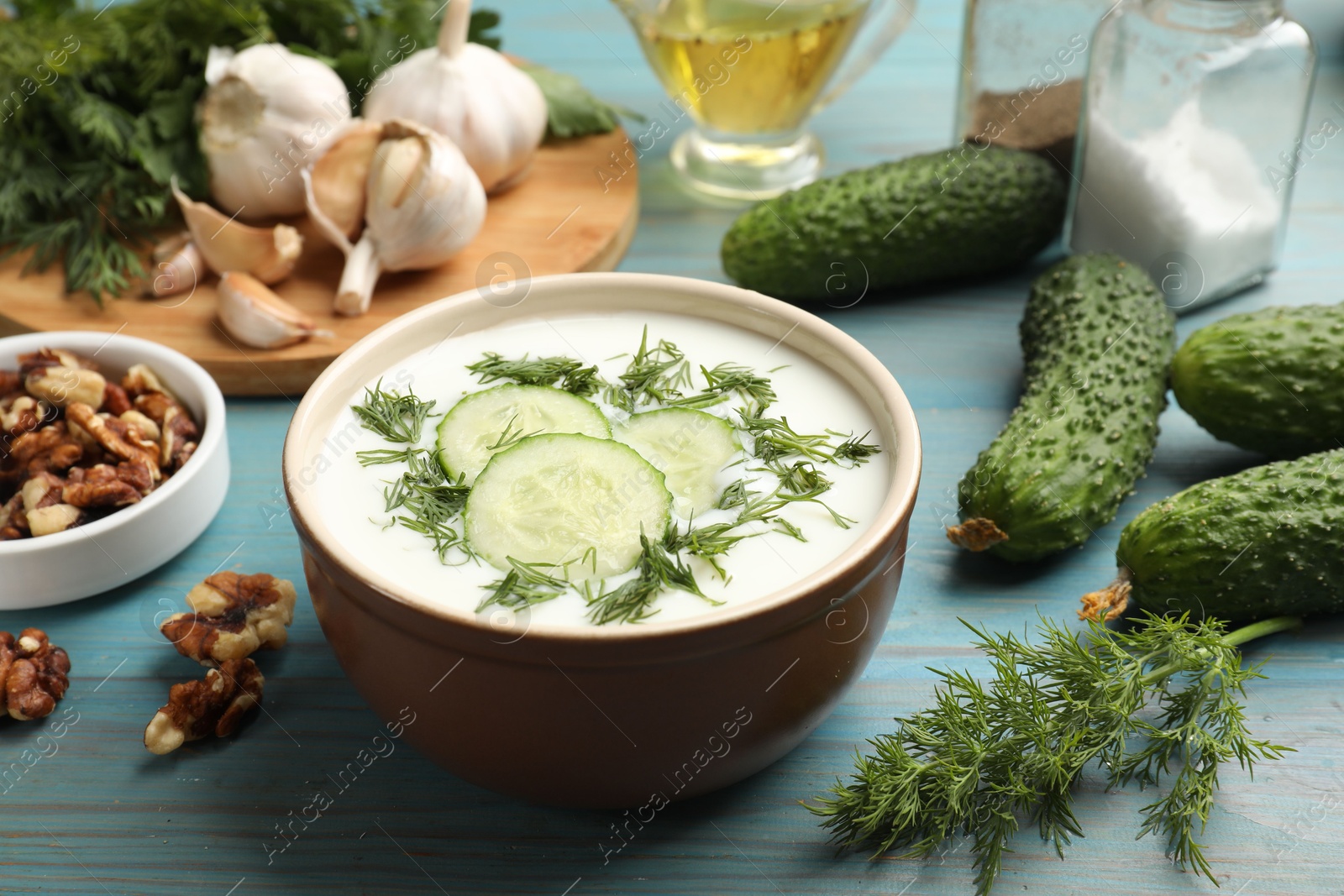 Tasty cucumber soup with dill among products on light blue wooden table, closeup Photo of Tasty cucumber soup with dill among products on light blue wooden table, closeup
