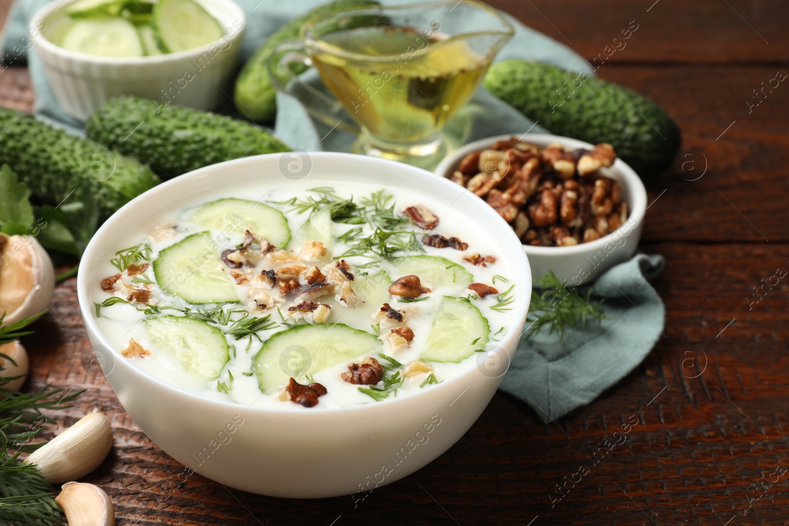 Tasty cucumber soup with dill and nuts in bowl on wooden table, closeup Photo of Tasty cucumber soup with dill and nuts in bowl on wooden table, closeup