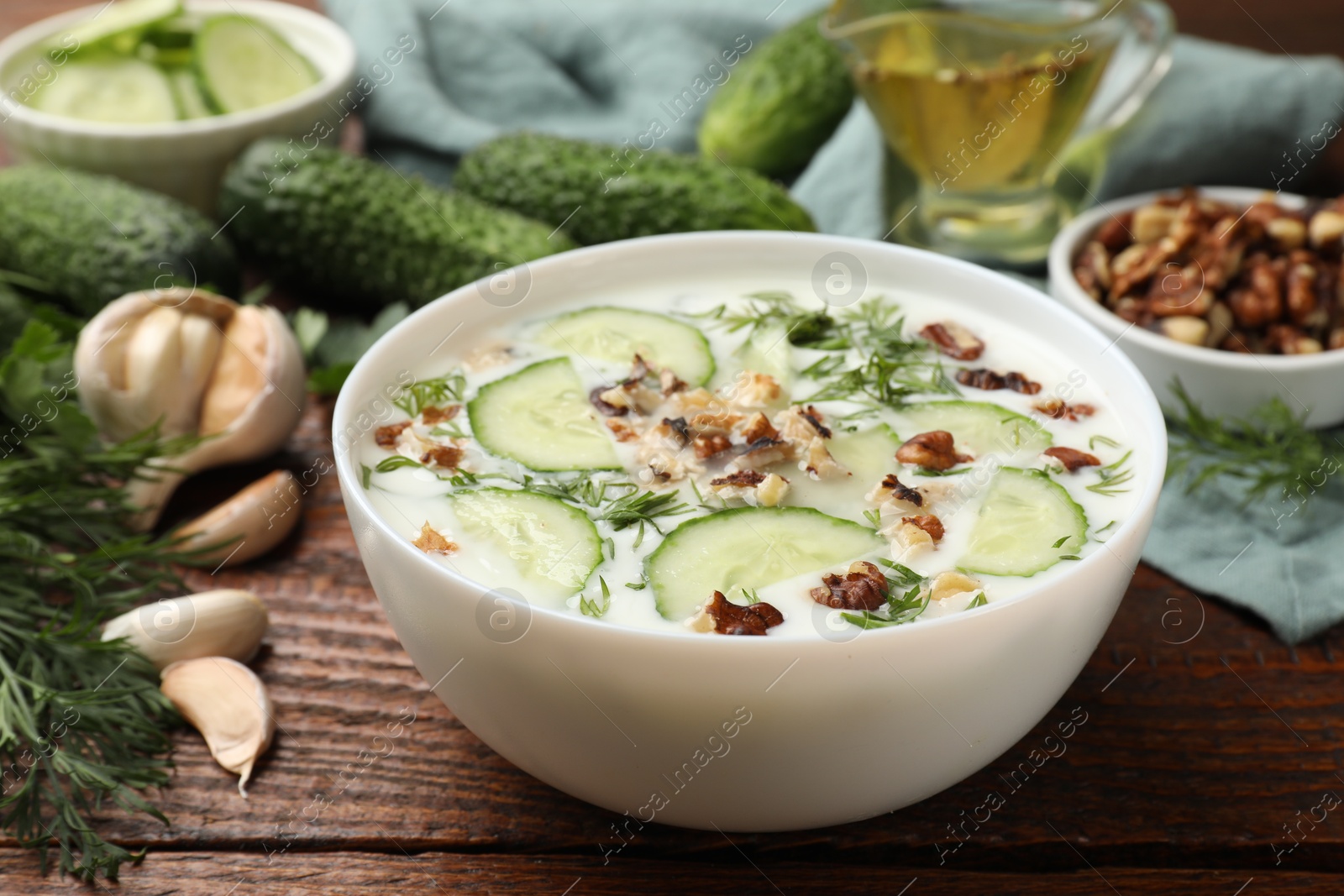 Tasty cucumber soup with dill and nuts in bowl on wooden table, closeup Photo of Tasty cucumber soup with dill and nuts in bowl on wooden table, closeup