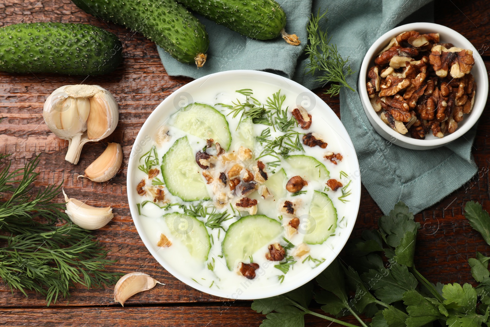 Tasty cucumber soup with dill, nuts and garlic on wooden table, flat lay Photo of Tasty cucumber soup with dill, nuts and garlic on wooden table, flat lay
