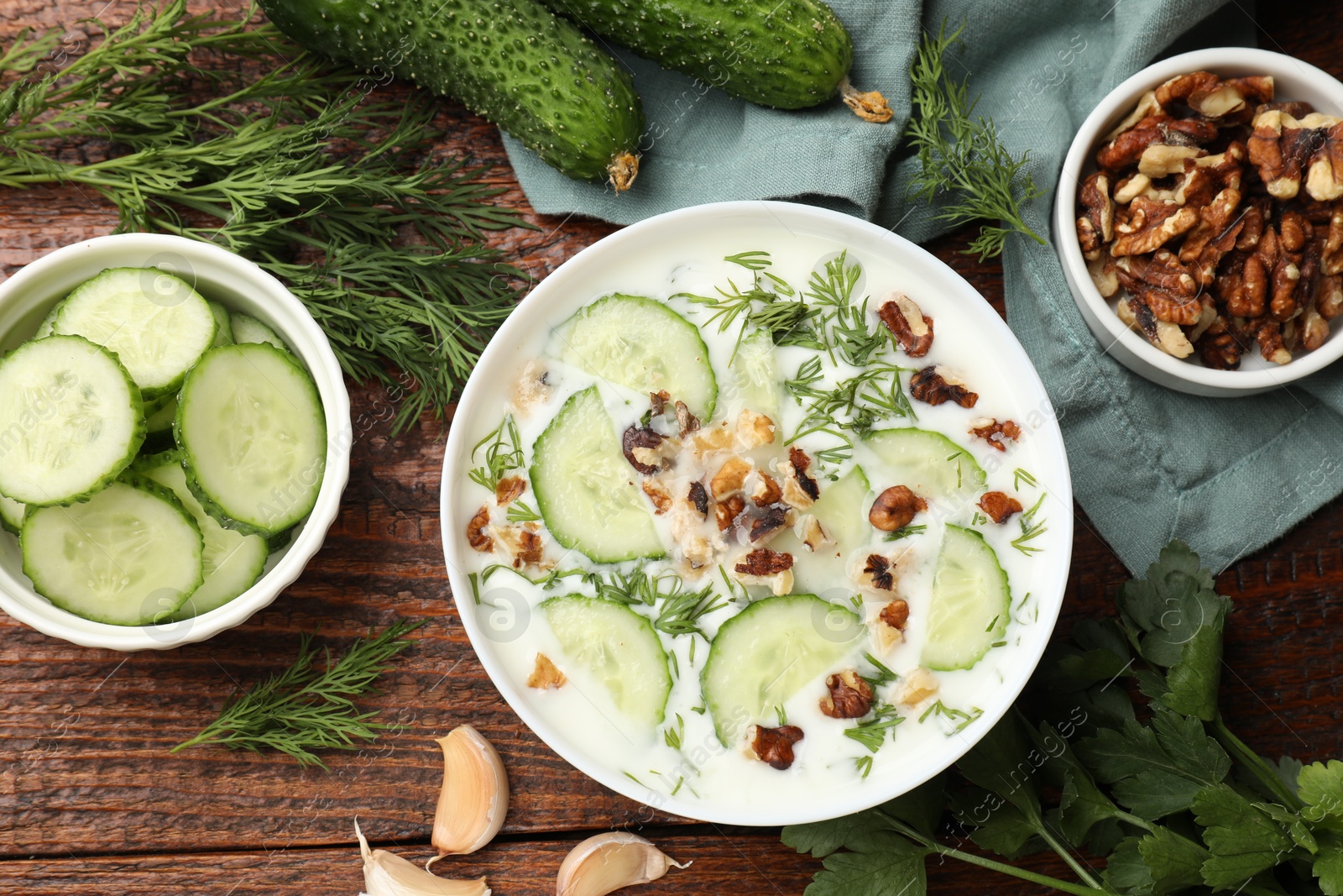 Tasty cucumber soup with dill, nuts and garlic on wooden table, flat lay Photo of Tasty cucumber soup with dill, nuts and garlic on wooden table, flat lay