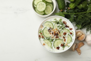 Photo of Tasty cucumber soup with dill, nuts and garlic on white table, flat lay. Space for text