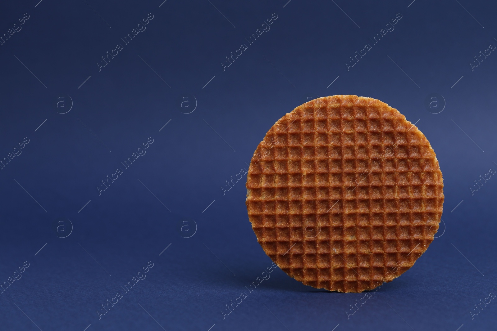 One tasty round waffle on blue background. Space for text Photo of One tasty round waffle on blue background. Space for text