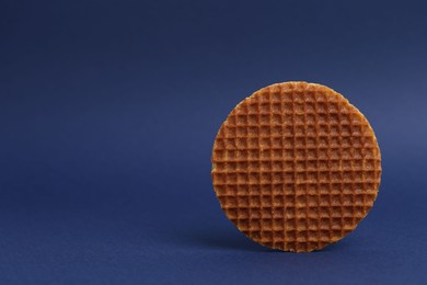 Photo of One tasty round waffle on blue background. Space for text