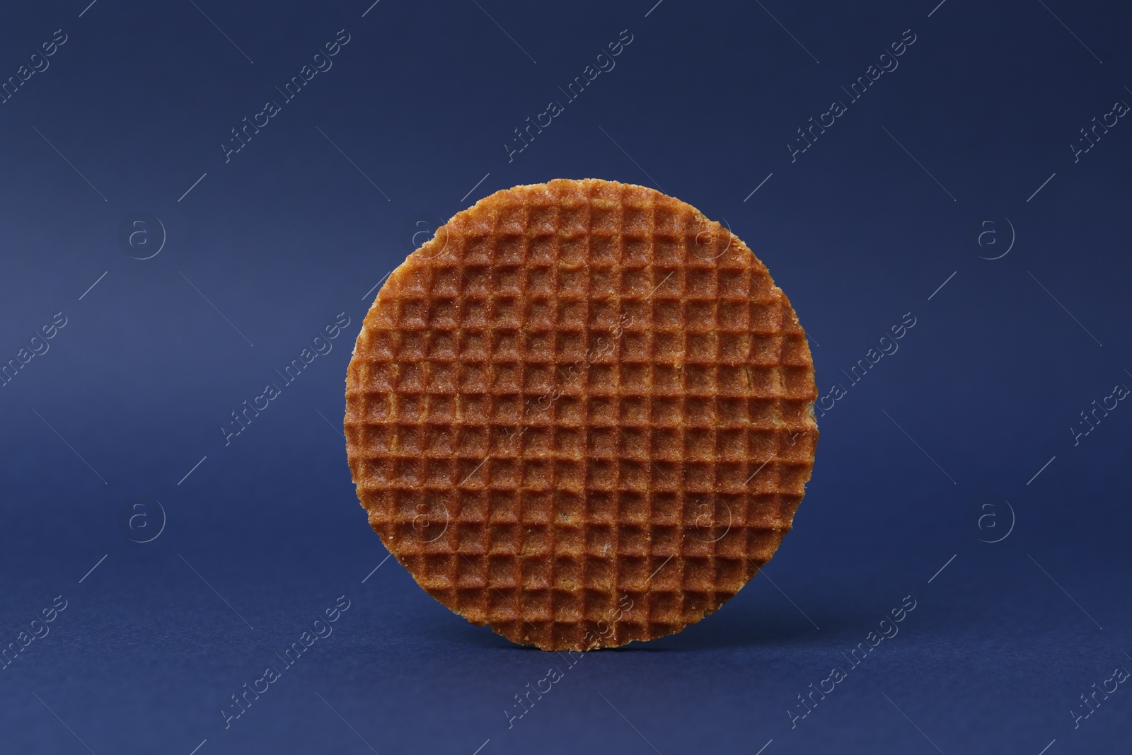 One tasty round waffle on blue background Photo of One tasty round waffle on blue background