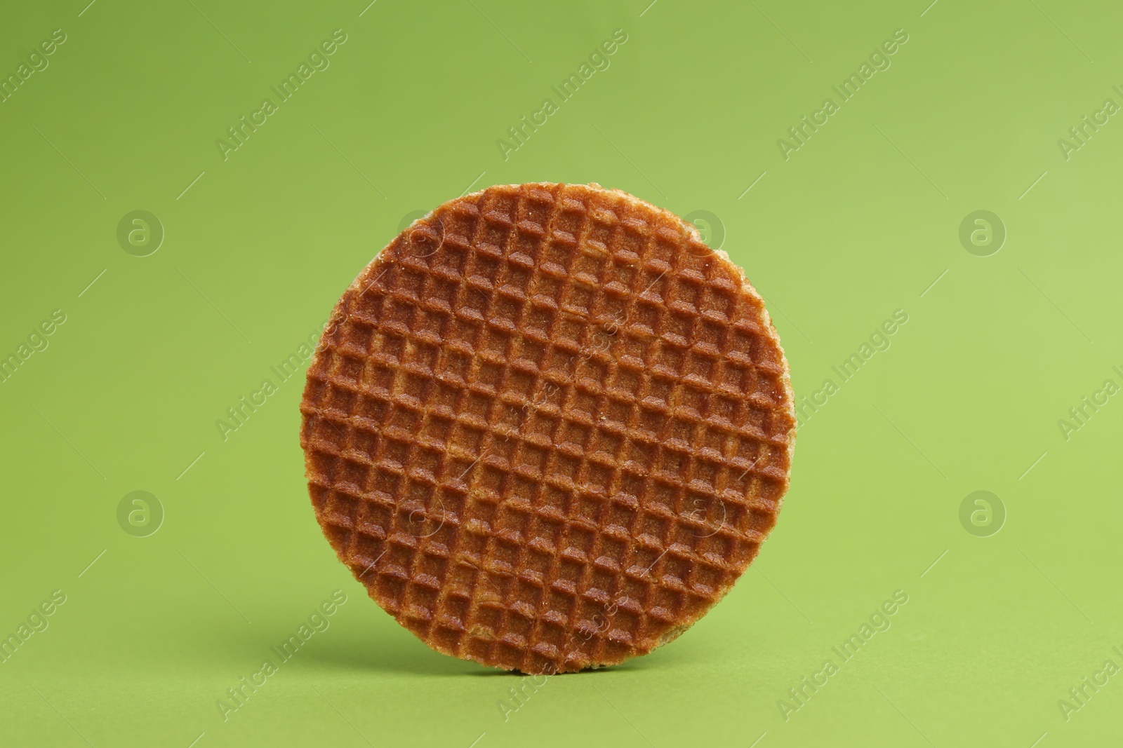 One tasty round waffle on green background Photo of One tasty round waffle on green background