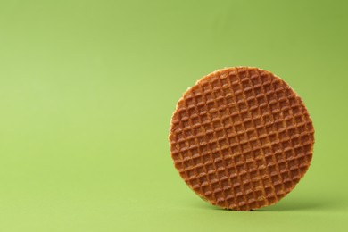 Photo of One tasty round waffle on green background. Space for text