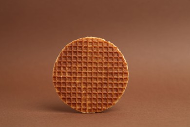 Photo of One tasty round waffle on brown background