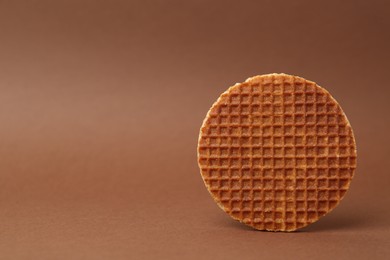 Photo of One tasty round waffle on brown background. Space for text