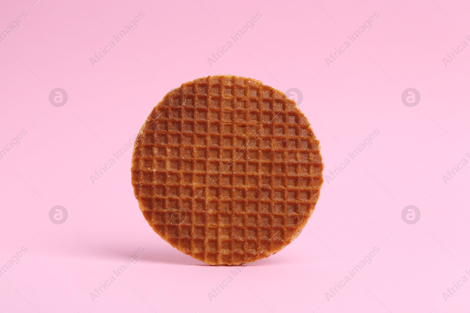 One tasty round waffle on pink background Photo of One tasty round waffle on pink background