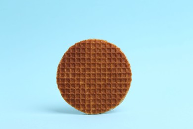 Photo of One tasty round waffle on light blue background