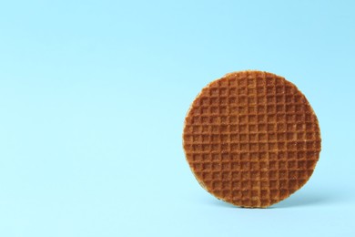 Photo of One tasty round waffle on light blue background. Space for text