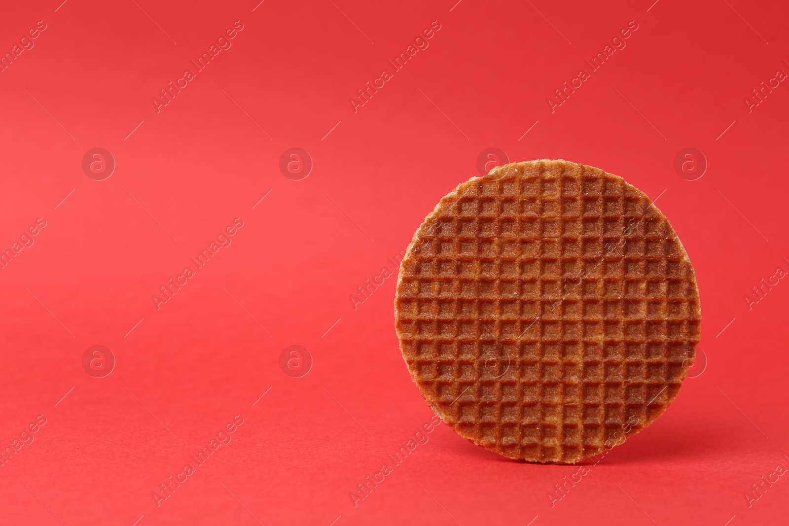One tasty round waffle on red background. Space for text Photo of One tasty round waffle on red background. Space for text