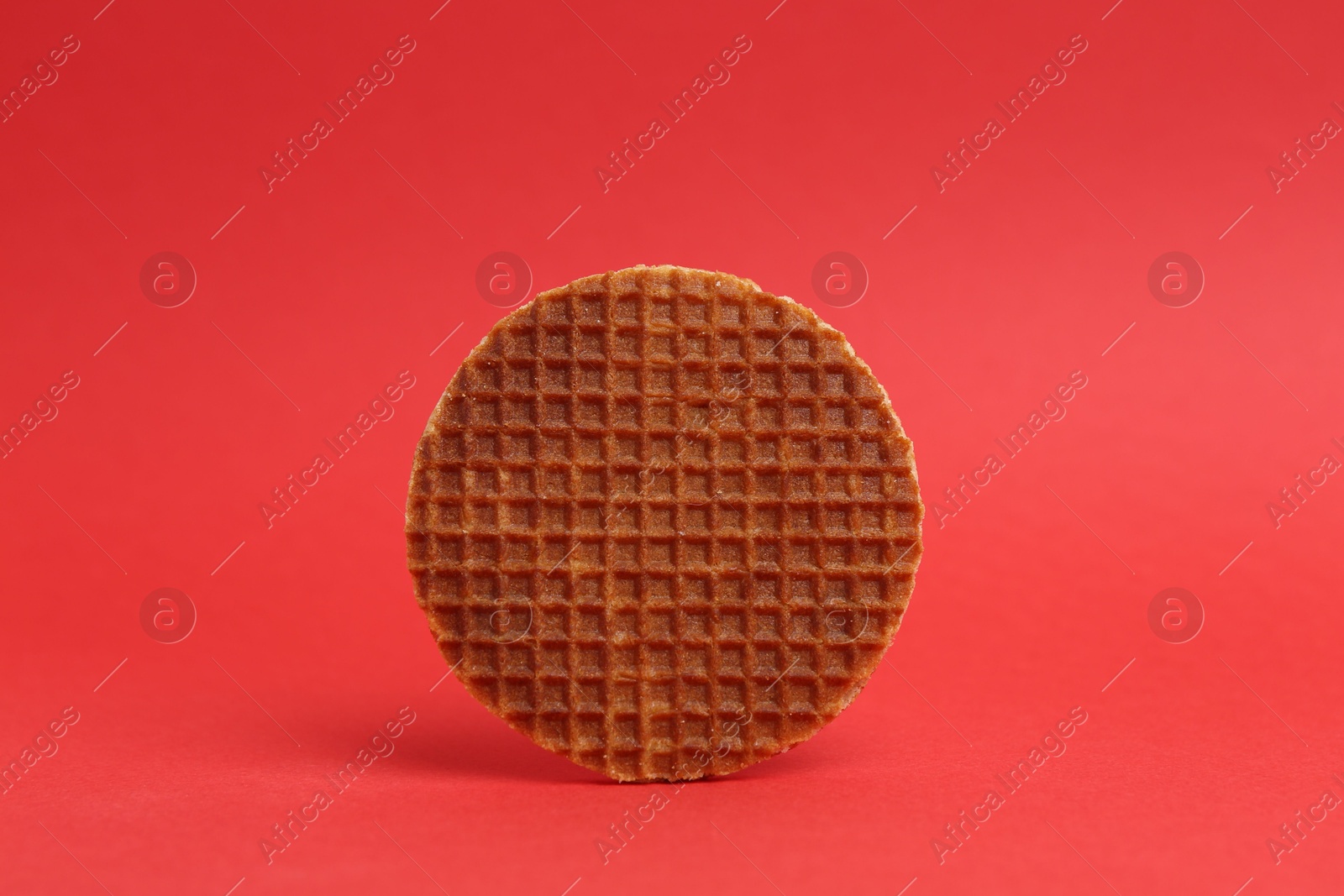 One tasty round waffle on red background Photo of One tasty round waffle on red background