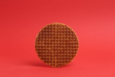Photo of One tasty round waffle on red background