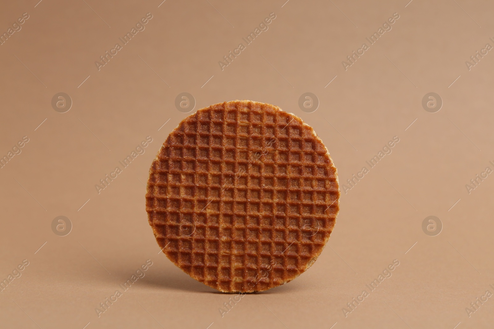 One tasty round waffle on brown background Photo of One tasty round waffle on brown background