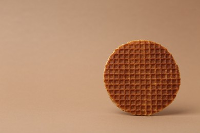 Photo of One tasty round waffle on brown background. Space for text