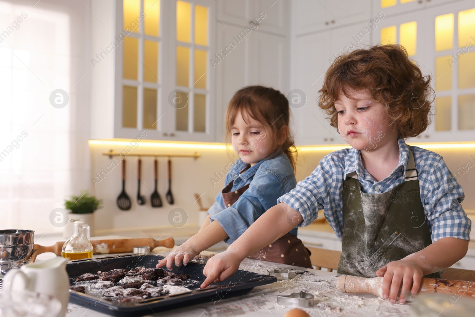 Cooking recipe. Children putting raw cookies onto baking dish at table in kitchen. Space for text Photo of Cooking recipe. Children putting raw cookies onto baking dish at table in kitchen. Space for text