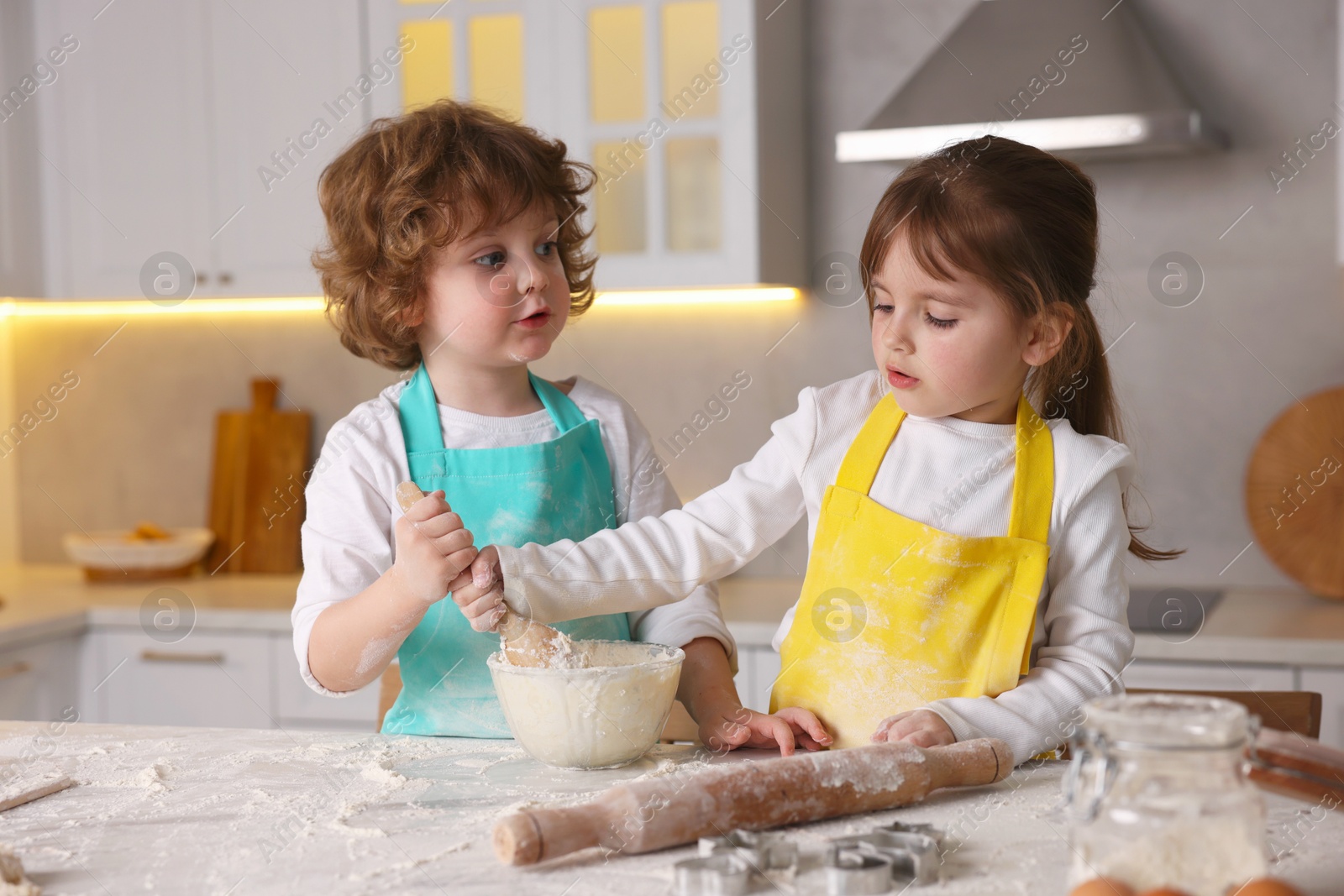 Cooking recipe. Cute children mixing dough for cookies at table in kitchen Photo of Cooking recipe. Cute children mixing dough for cookies at table in kitchen