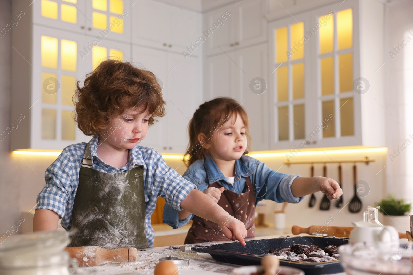 Cooking recipe. Children putting raw cookies onto baking dish at table in kitchen Photo of Cooking recipe. Children putting raw cookies onto baking dish at table in kitchen