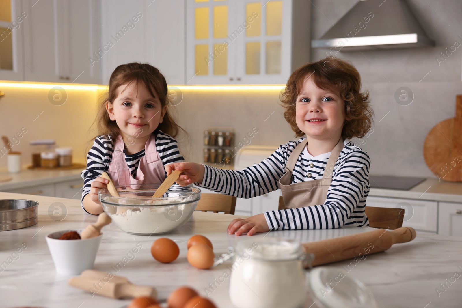 Cooking recipe. Cute children making dough for cookies at table in kitchen Photo of Cooking recipe. Cute children making dough for cookies at table in kitchen