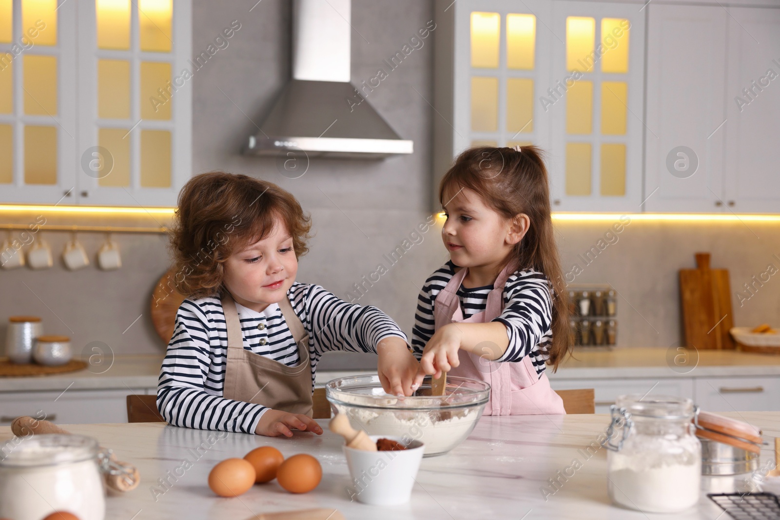 Cooking recipe. Cute children making dough for cookies at table in kitchen Photo of Cooking recipe. Cute children making dough for cookies at table in kitchen
