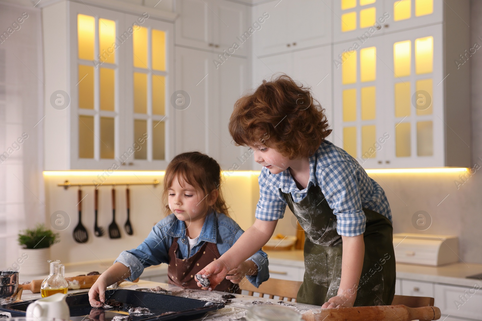 Cooking recipe. Children putting raw cookies onto baking dish at table in kitchen Photo of Cooking recipe. Children putting raw cookies onto baking dish at table in kitchen