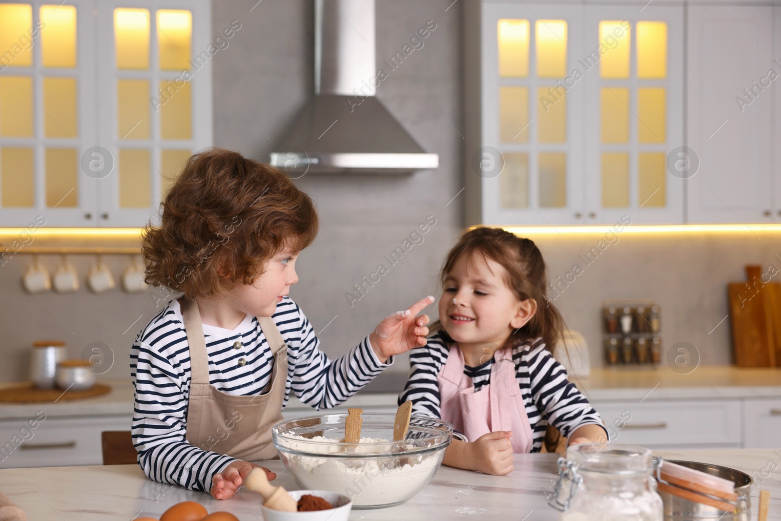Cooking recipe. Little children making dough for cookies at table in kitchen Photo of Cooking recipe. Little children making dough for cookies at table in kitchen
