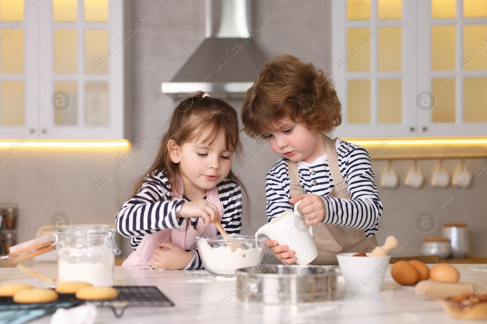 Cooking recipe. Cute children making dough for cookies at table in kitchen Photo of Cooking recipe. Cute children making dough for cookies at table in kitchen