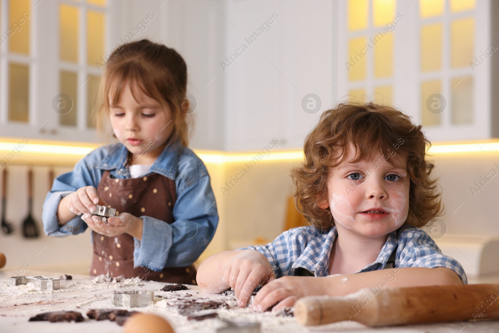 Cooking recipe. Little children cutting cookie dough with cutters at table indoors Photo of Cooking recipe. Little children cutting cookie dough with cutters at table indoors