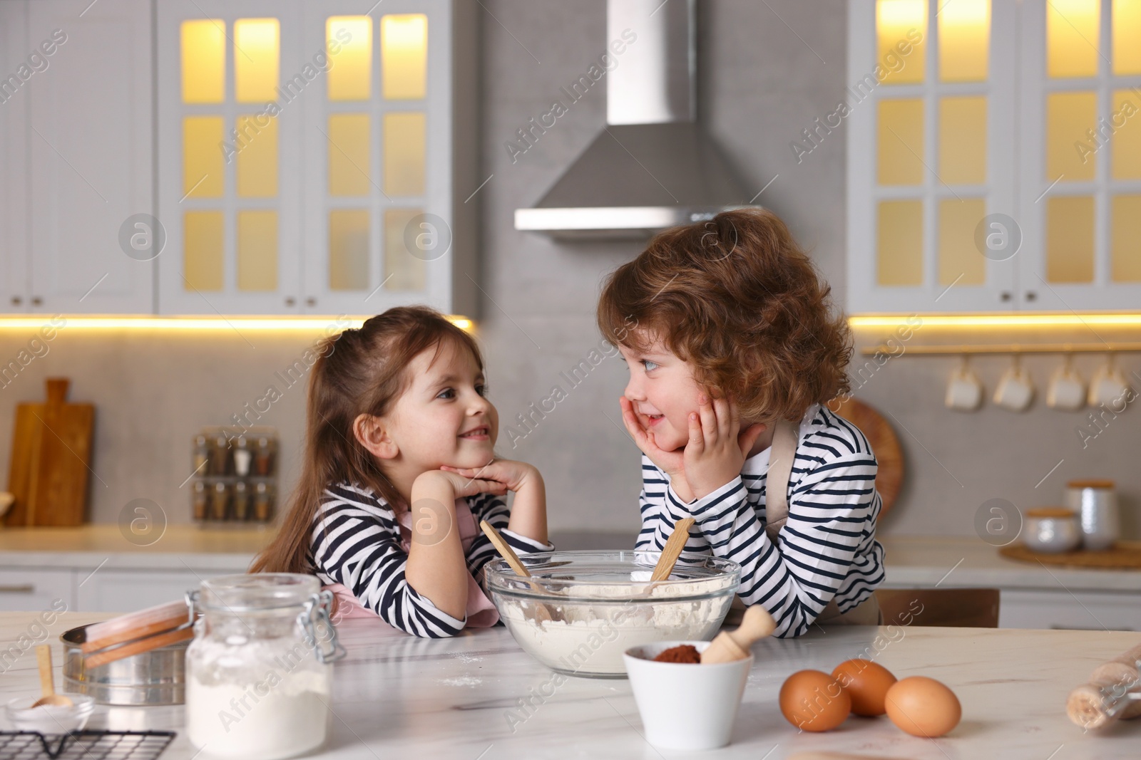Cooking recipe. Little children making dough for cookies at table in kitchen Photo of Cooking recipe. Little children making dough for cookies at table in kitchen