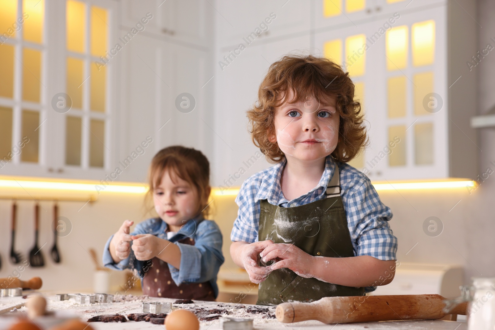 Cooking recipe. Little children cutting cookies with cutters at table in kitchen Photo of Cooking recipe. Little children cutting cookies with cutters at table in kitchen