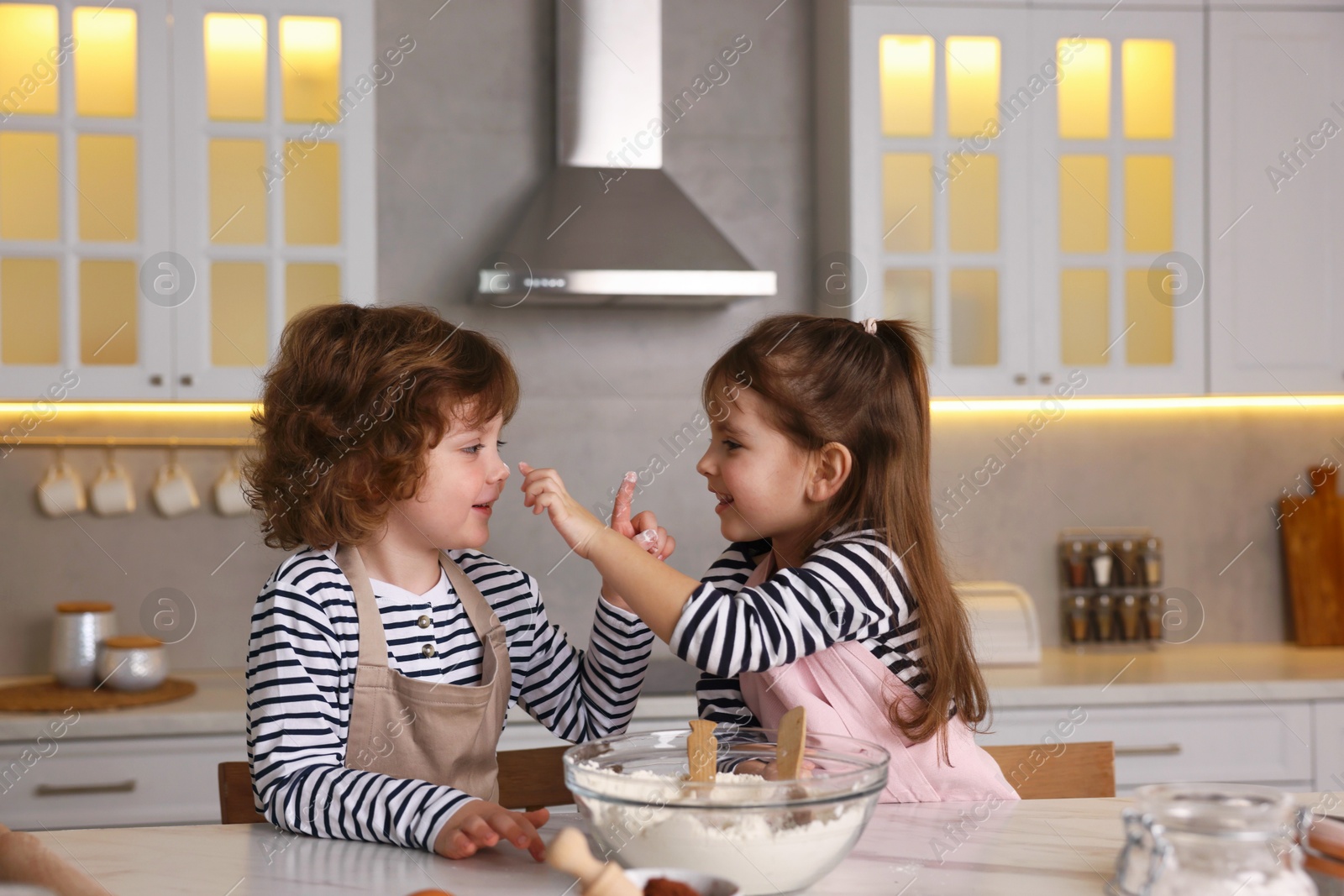 Cooking recipe. Little children making dough for cookies at table in kitchen Photo of Cooking recipe. Little children making dough for cookies at table in kitchen