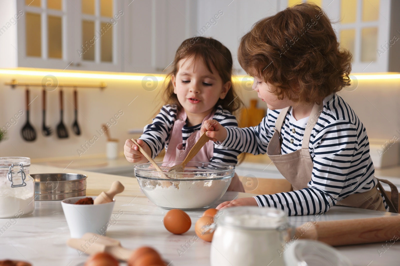 Cooking recipe. Cute children making dough for cookies at table in kitchen Photo of Cooking recipe. Cute children making dough for cookies at table in kitchen