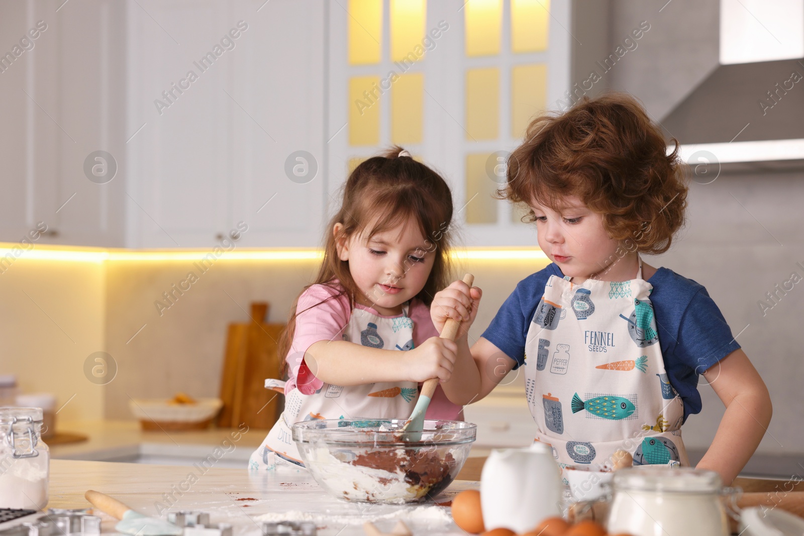 Cooking recipe. Cute children mixing dough for cookies at table in kitchen Photo of Cooking recipe. Cute children mixing dough for cookies at table in kitchen