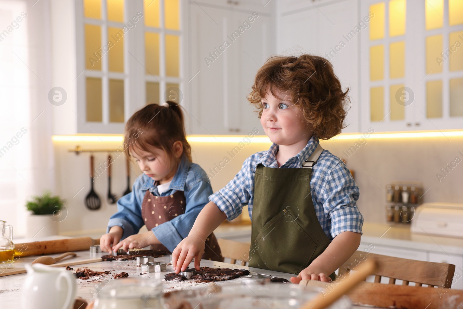 Cooking recipe. Little children cutting cookie dough with cutters at table indoors Photo of Cooking recipe. Little children cutting cookie dough with cutters at table indoors