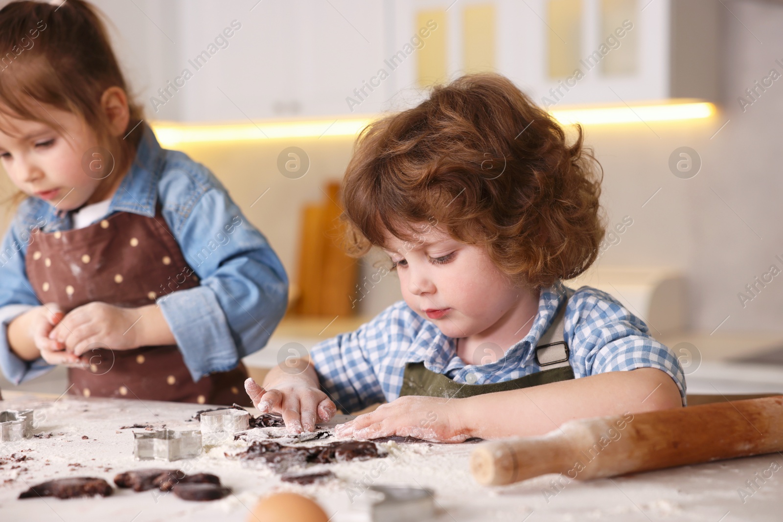 Cooking recipe. Little children cutting cookie dough with cutters at table indoors Photo of Cooking recipe. Little children cutting cookie dough with cutters at table indoors