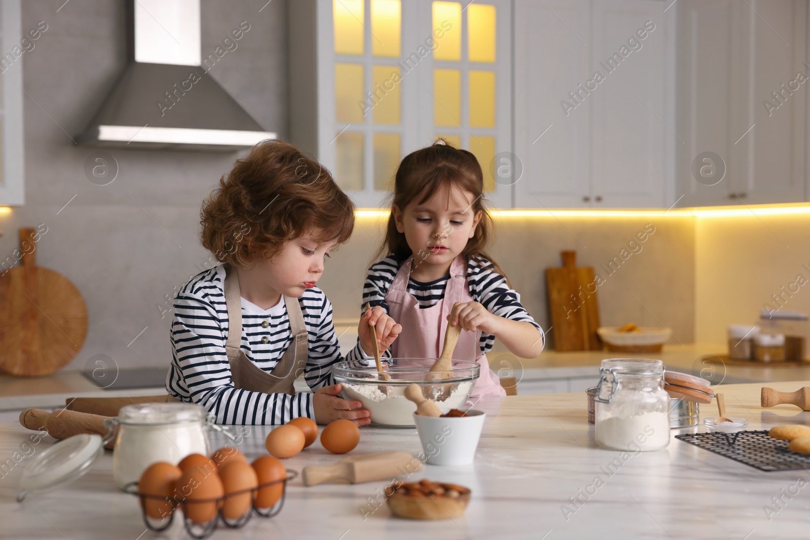 Cooking recipe. Cute children making dough for cookies at table in kitchen Photo of Cooking recipe. Cute children making dough for cookies at table in kitchen