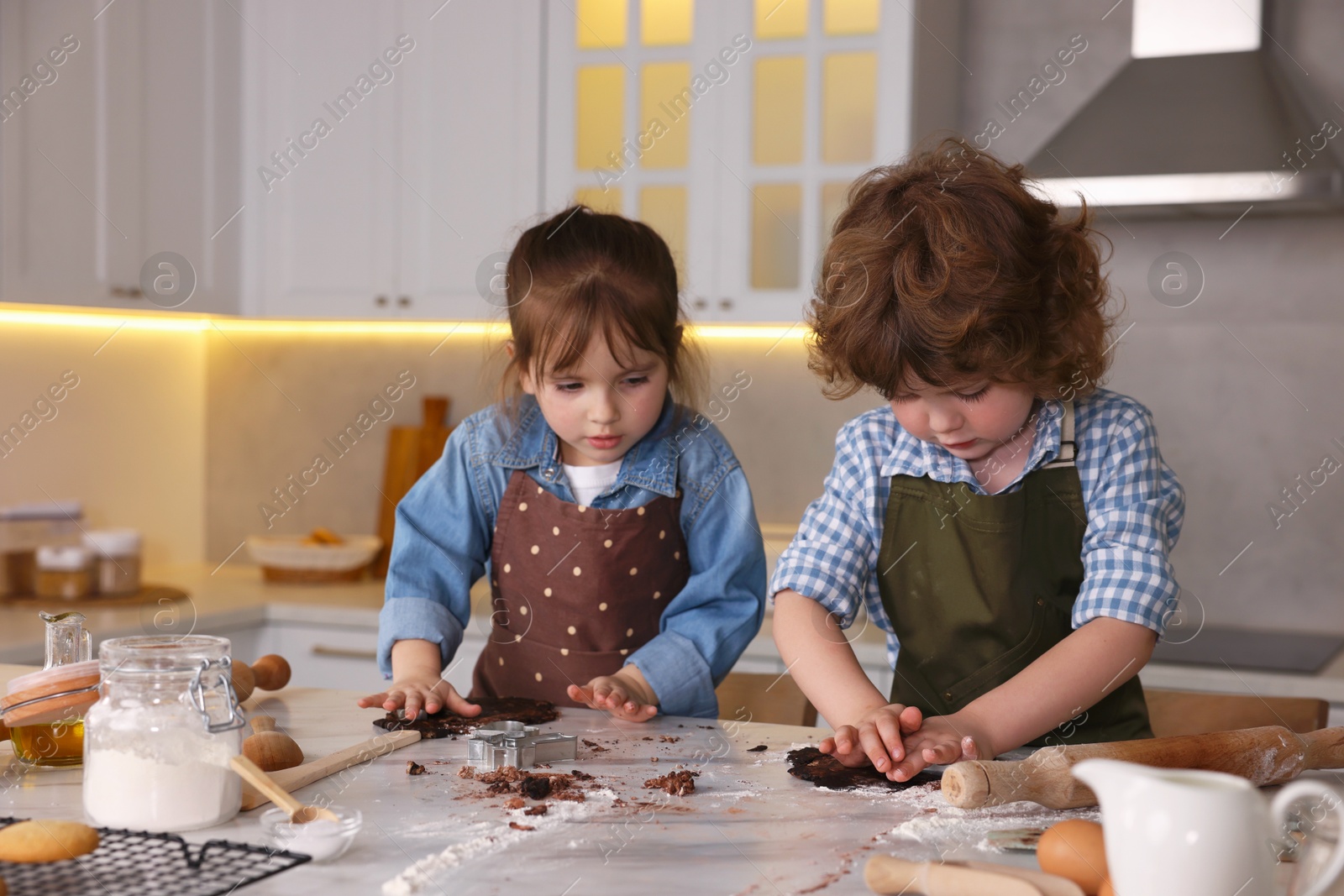 Cooking recipe. Little children cutting cookie dough with cutters at table indoors Photo of Cooking recipe. Little children cutting cookie dough with cutters at table indoors