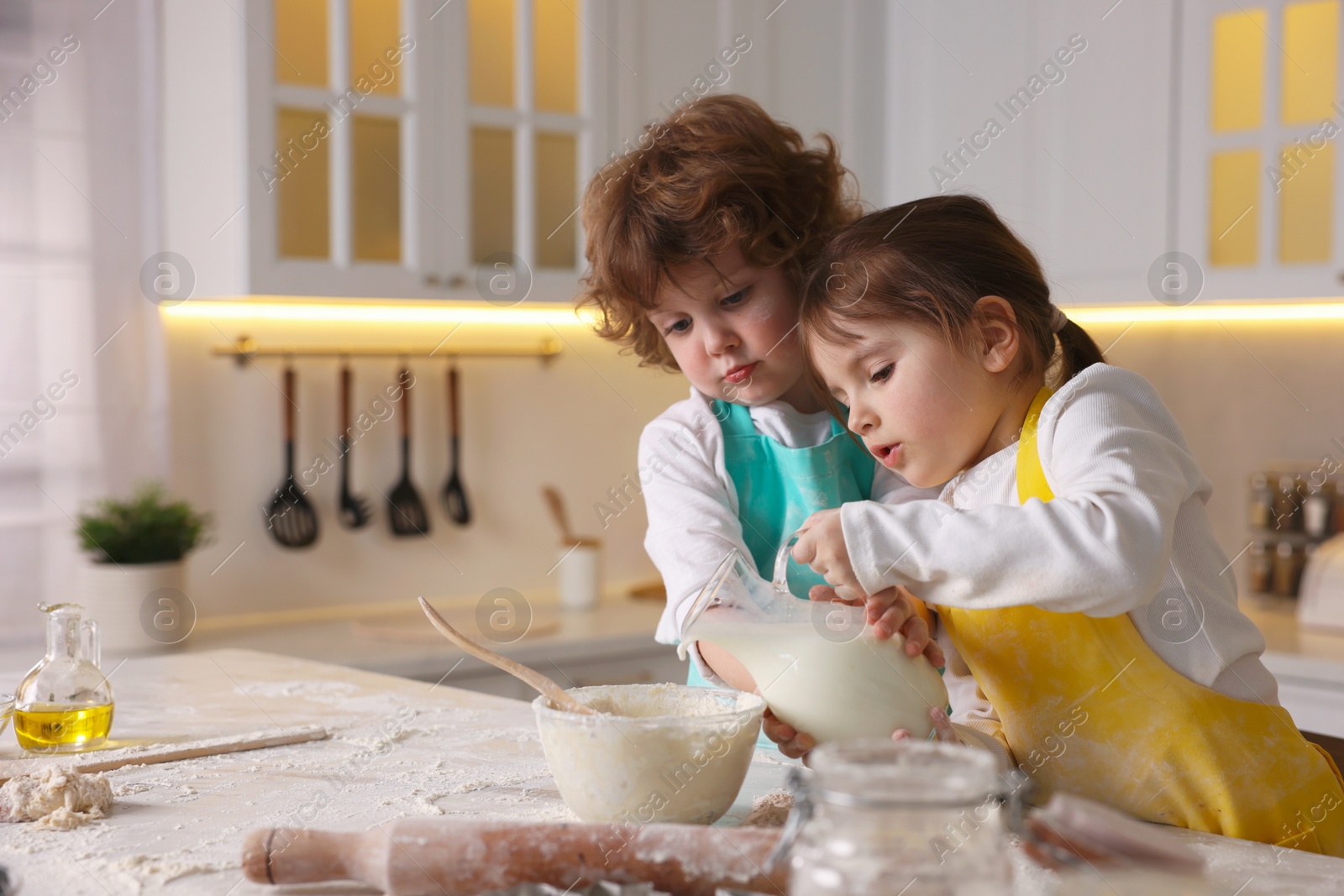 Cooking recipe. Cute children making dough for cookies at table in kitchen Photo of Cooking recipe. Cute children making dough for cookies at table in kitchen